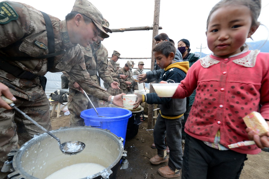 27日、被災地の子どもに朝食を配る解放軍救援隊。