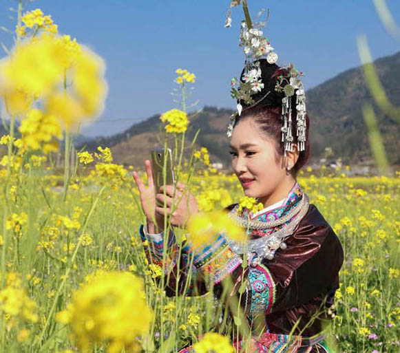 トン族の村に春來たる、花と戯むる村の女性たち