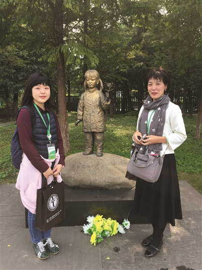 バウヒニアの花を持つ少女の像の前に立つ佐々木真理子さんと古谷恵莉子さん。