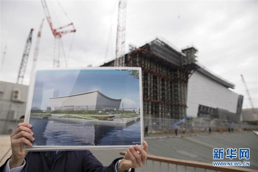 2月12日、東京「有明アリーナ」の建設現(xiàn)場で、完成予想図を手にする関係者。バレーボール競技とパラリンピックの車いすバスケットボールの試合がここで行われる計畫。1月末の時點で51％が完成している（撮影?杜瀟逸）。 