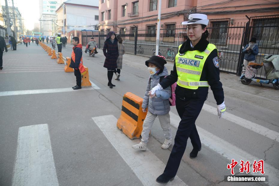 子供の手を引いて一緒に道路を橫斷する交通警察官（撮影?劉文華）。