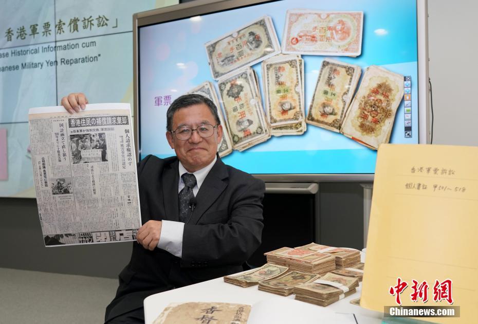 「香港軍票訴訟」関連の歴史資料を見せる和仁廉夫氏 (撮影?張■、■は火へんに韋)。