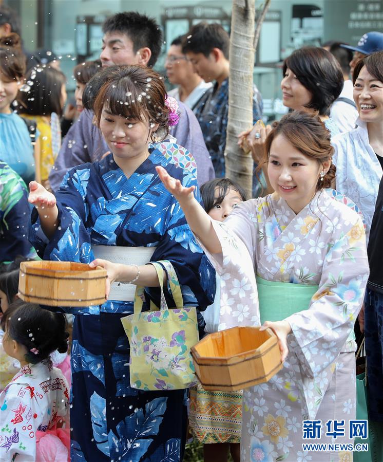 東京?銀座のイベント會場となった通りで、浴衣姿で打ち水をする女性（撮影?杜瀟逸）。