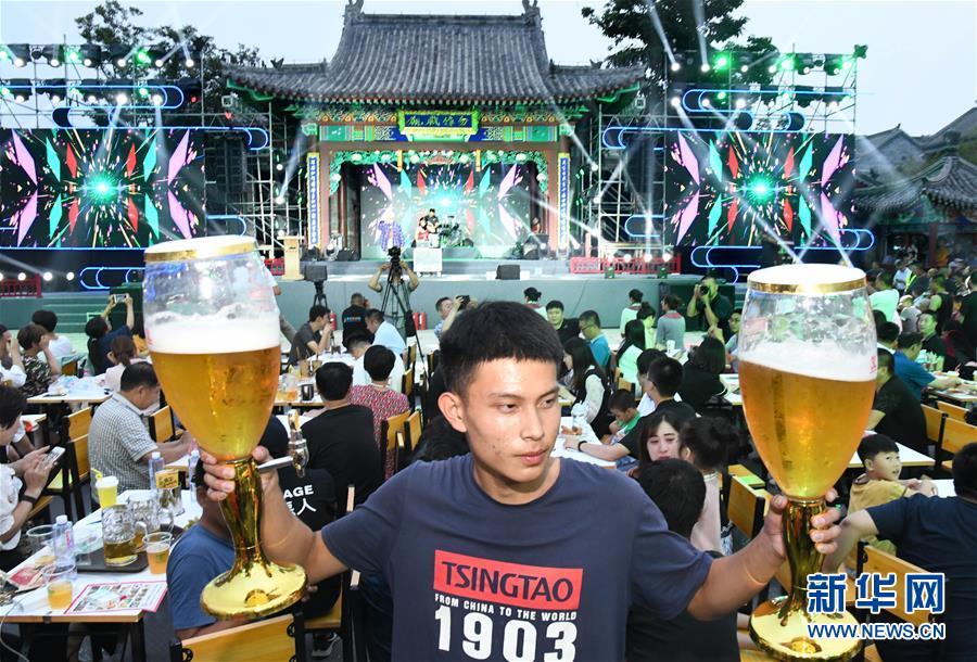 山東省青島市の國際ビール祭り(即墨古城會場)で大きなビールグラスを両手に持つ男性（7月12日撮影?李紫恒）。