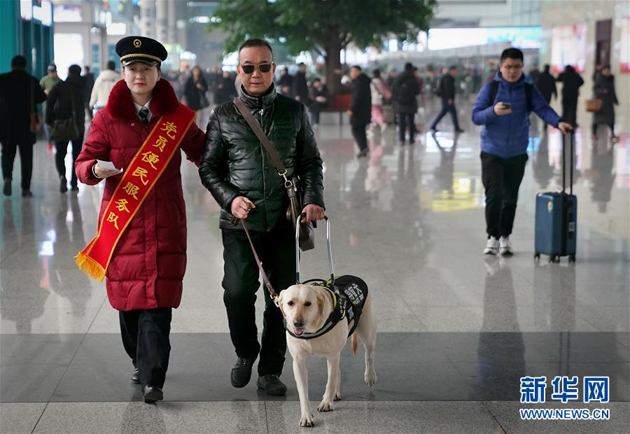 目の不自由な乗客の靳さんと盲導(dǎo)犬の「小七」を駅構(gòu)內(nèi)の待合室まで案內(nèi)する鄭州東駅のスタッフ（1月14日に撮影?李安）。