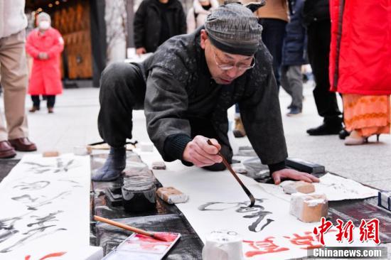 2月9日、日本の書家?篆刻家である鈴木啓義氏が武漢の幸福を祈り東京の街頭で揮毫した（撮影?呂少威）。