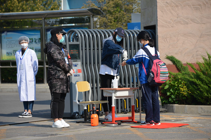 資料寫真、北京市昌平二中回竜観キャンパスの校門で體溫測(cè)定を受ける學(xué)生（畫像提供?北京教育ニュースセンター）。