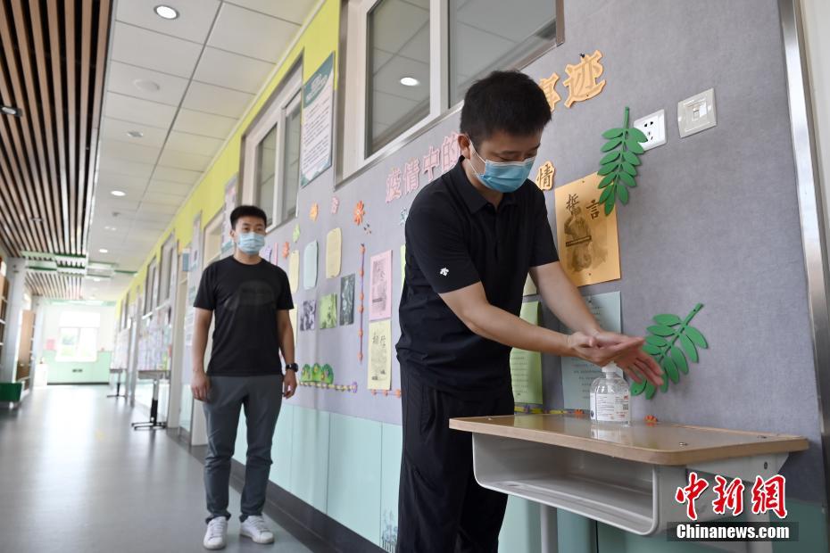 8月24日、北京教育學院附屬豊臺実験學校で、教室に入る前に手の消毒を行う教職員。同校の全教室の入口には、新學期開始後に生徒が使用できるように、消毒ジェルなどの防疫用品が設置されている（撮影?張興龍）。