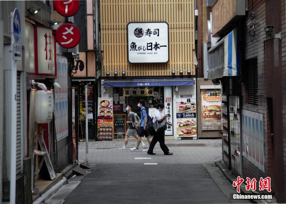 東京で、すし屋の前を通り過ぎる市民（撮影?呂少威）。