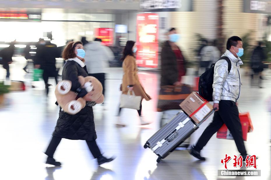 クマのぬいぐるみを抱えたり、キャリーカートの荷物を手に南京鉄道駅構(gòu)內(nèi)に移動(dòng)する乗客（撮影?泱波）。