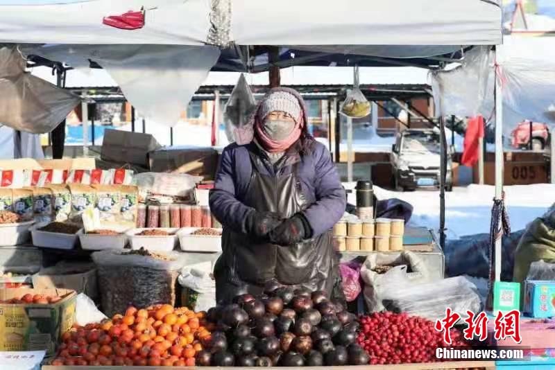 しっかり著込んで東北名物の凍果を売る漠河市の露店経営者（撮影?王景陽）。