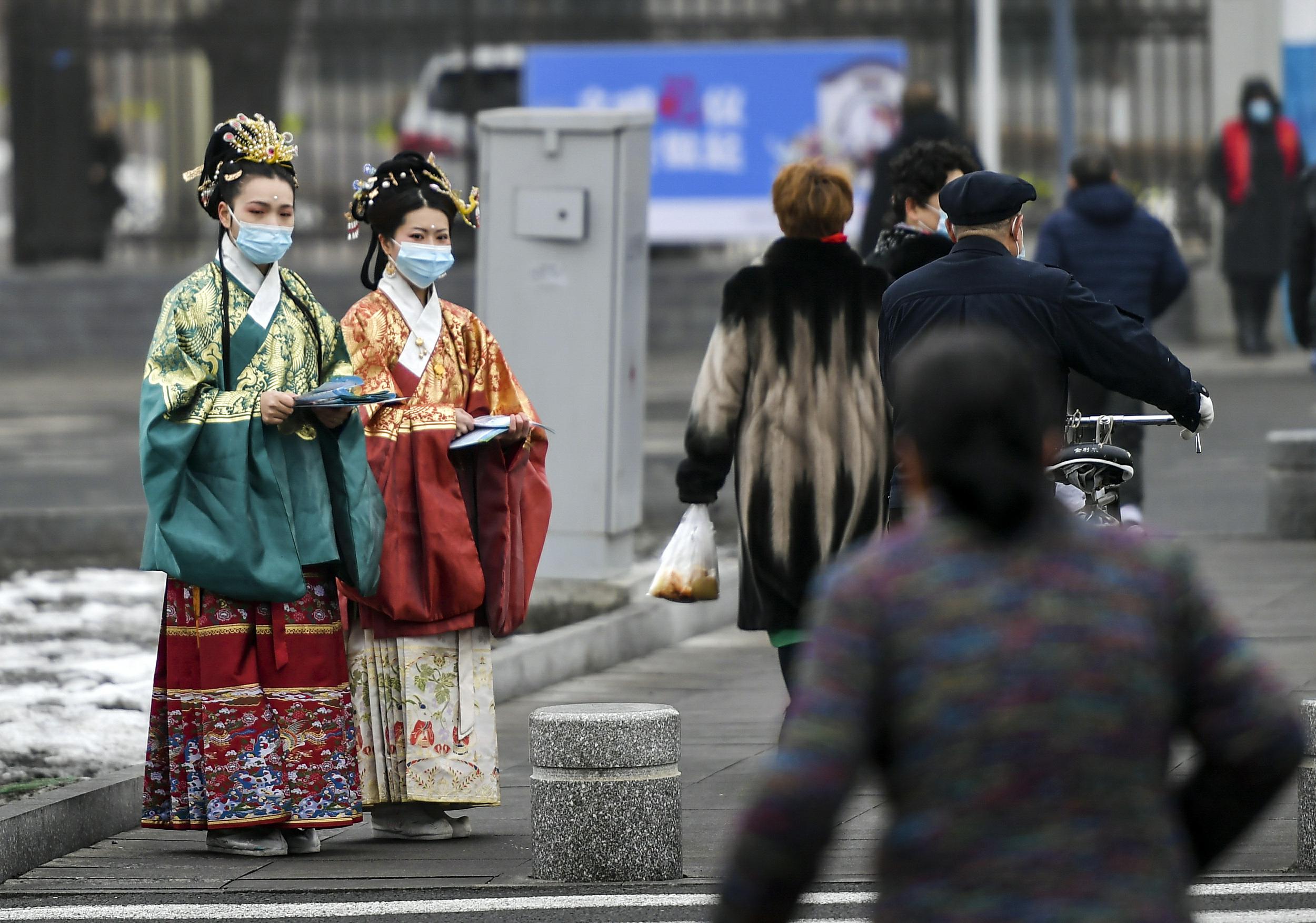 3月10日、新疆ウルムチ市ハイテク區(qū)（新市區(qū)）の北京路で、交通ルールやマナーを守った外出を通行者に呼びかける、漢服姿のボランティア（寫真著作権はCFP視覚中國が所有のため転載禁止）。