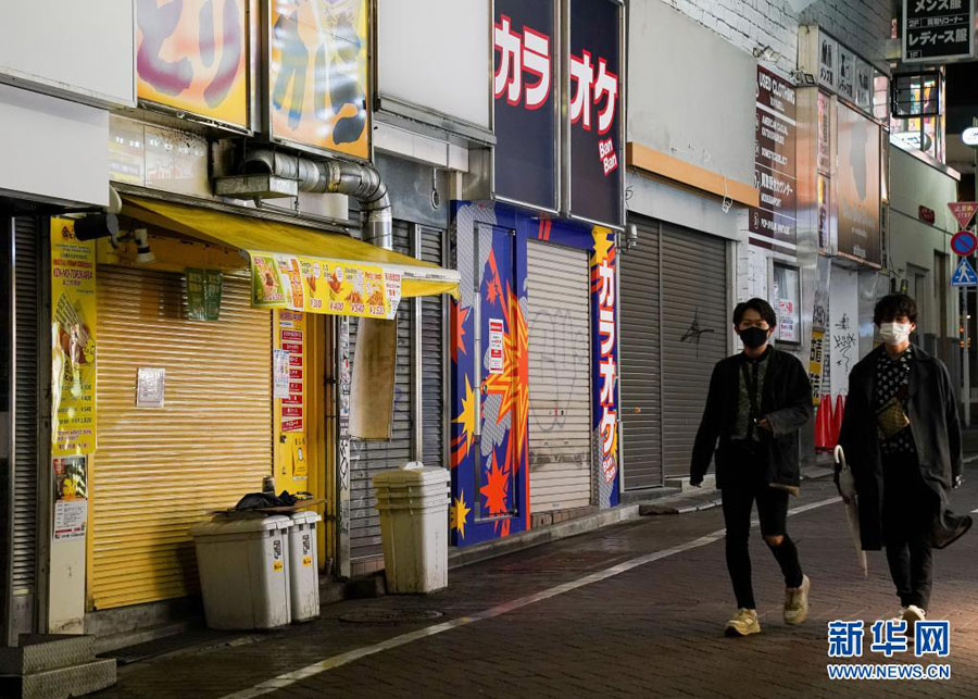 5月7日、店のシャッターが閉まり閑散とした商店街を歩く男性。