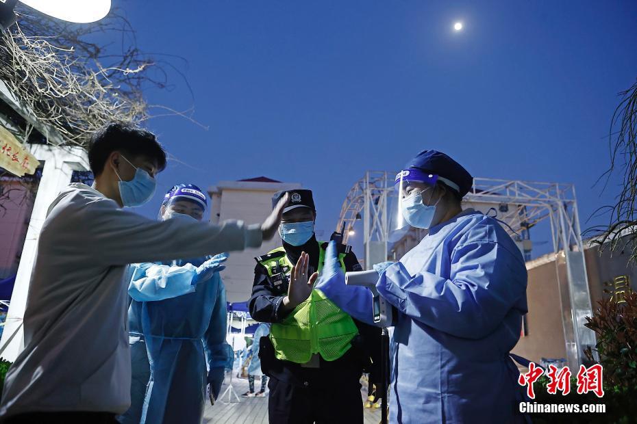 虹橋空港新村で15日、警察官に率いられ、PCR検體採取前の検溫を受ける住民（撮影?殷立勤）。