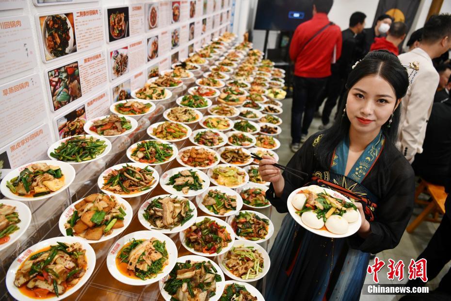 自らが作った「ニンニクの芽回鍋肉」を見せる、「108種類の回鍋肉メニュー」を企畫した羅程丹さん（撮影?張浪）。