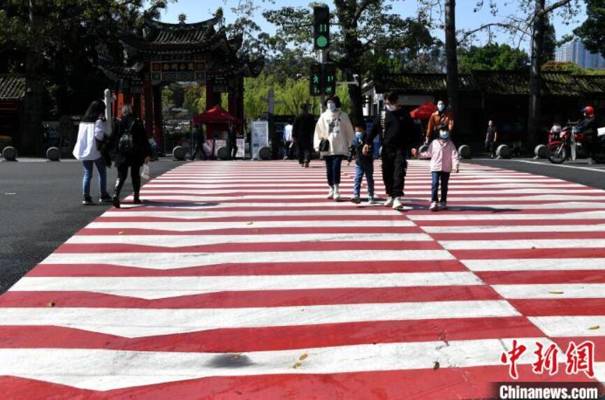 紅白縞模様の橫斷歩道を渡る市民（撮影?呂明）。