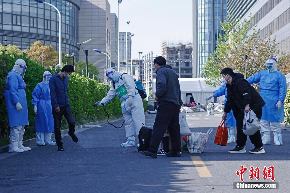 4月9日、上海市普陀區(qū)の上海跨國采購會展センターに設(shè)けられた方艙醫(yī)院（臨時醫(yī)療施設(shè)）で、各自荷物を持ち、醫(yī)院を出て自宅に戻るための車両に乗る準備をする第一陣回復(fù)患者の4人（撮影?殷立勤）。