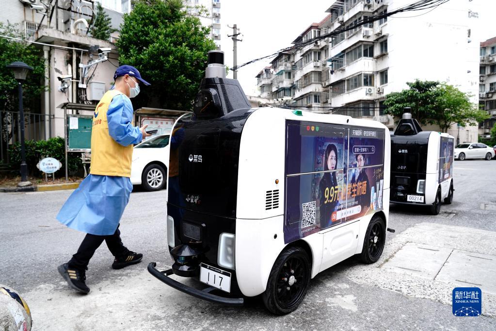 4月25日、コミュニティ入口で配送物を無人配送車に入れる上海市楊浦區(qū)長海路街道（エリア）浣紗小區(qū)（コミュニティ）の黨員ボランティア（撮影?張建松）。