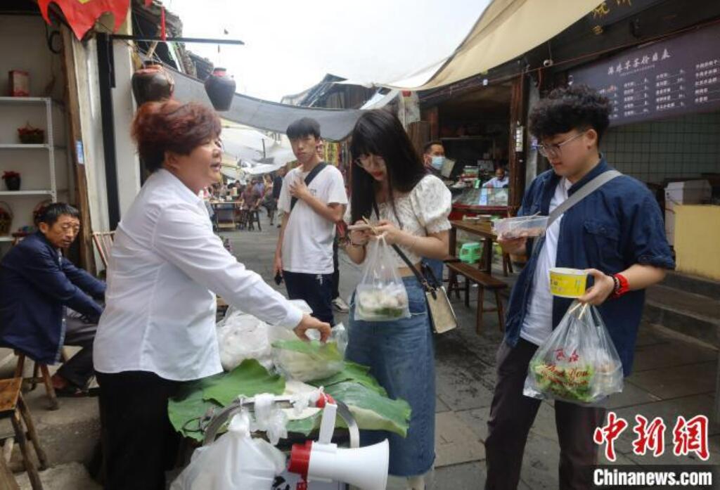 屋臺(tái)で餅菓子「麻糍」を購入するマカオ出身の學(xué)生?程芊慧さん（寫真一番右）と同級(jí)生（撮影?董易鑫）。