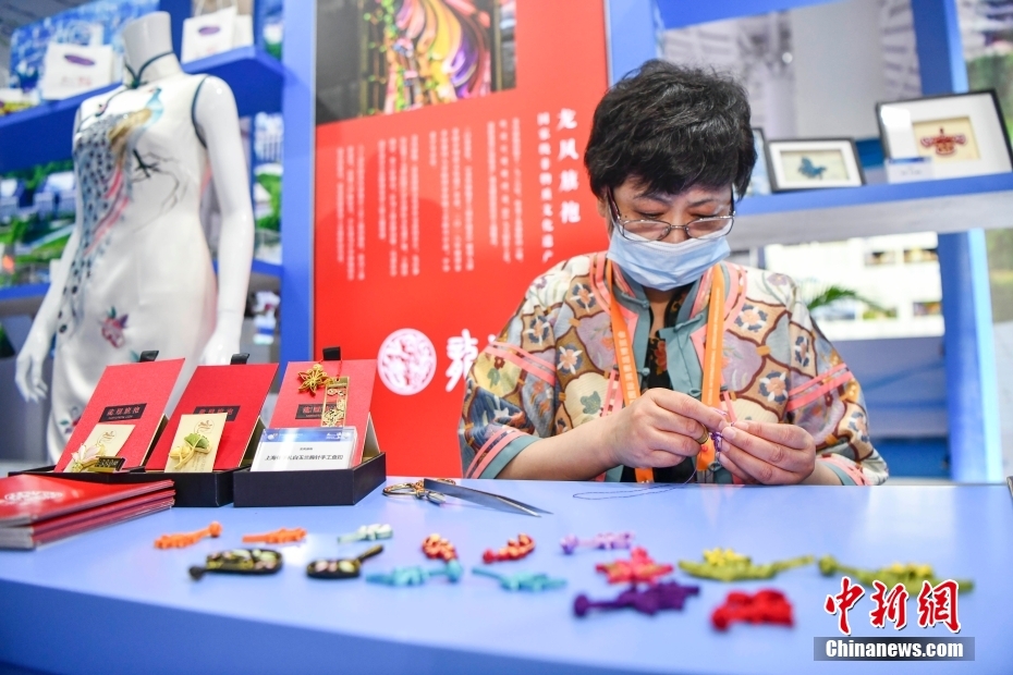 上海館に設(shè)けられた中國の老舗チャイナドレスブランド「竜鳳旗袍」展示ブースで、チャイナドレスのボタンの制作技法を披露する無形文化遺産伝承者（撮影?駱雲(yún)飛）。