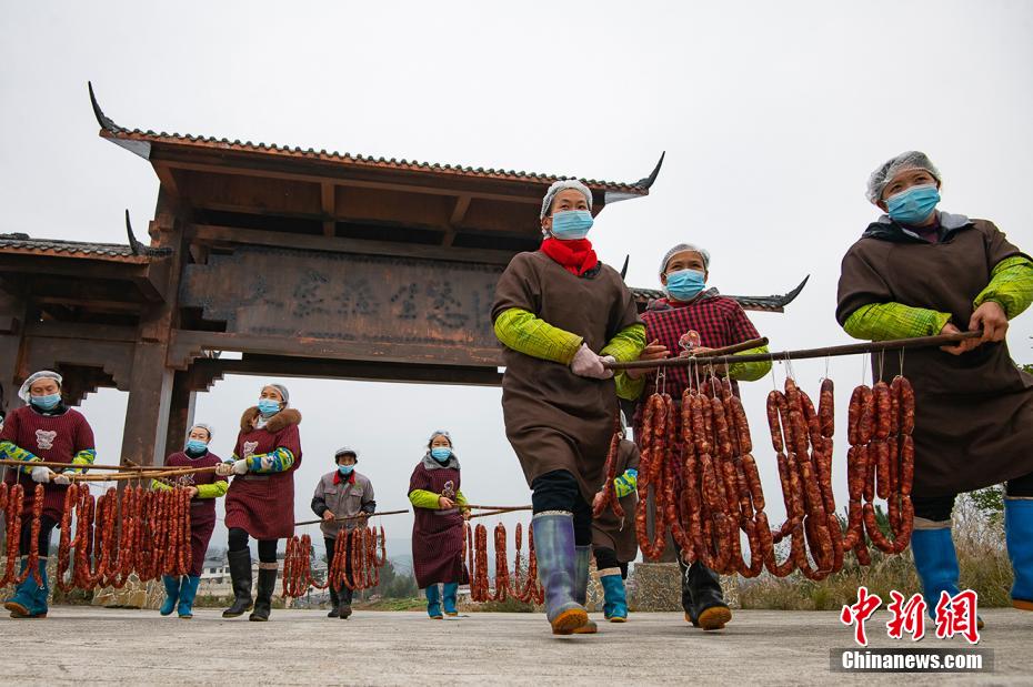 出來上がったばかりの腸詰めを乾燥場まで運ぶ村人たち（撮影?冉孟軍）。