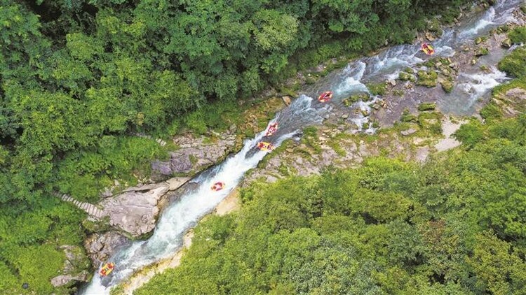 鎮(zhèn)遠高過河景勝地でラフティングを楽しむ観光客。山には緑の木々が茂り、その間を流れる川の水は川底が見えるほど透き通っており、川幅が狹くなったり、広くなったりしている。（ドローンで撮影）