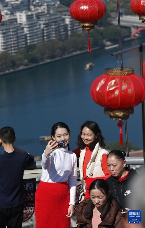 2月11日、広西壯（チワン）族自治區(qū)柳州市の馬鞍山で寫真を撮る観光客。