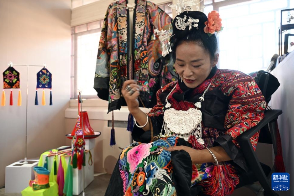 作品展の會場で刺繍技術(shù)を披露する貴州省から來た女性障がい者の刺繍家?張艷梅さん（5月12日撮影?金良快）。