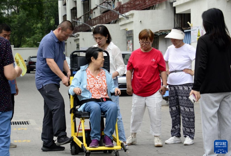 北京市朝陽(yáng)區(qū)青年路社區(qū)にある古い社區(qū)で、「可搬型階段昇降機(jī)」の使い方を?qū)Wぶ住民（7月11日撮影?李欣）。