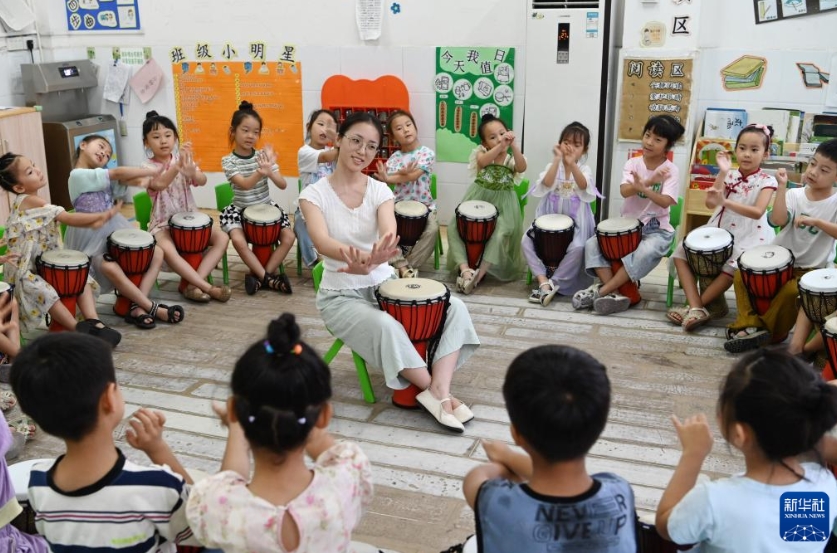 河南省沁陽(yáng)市の第一幼稚園教育集団白荘村幼稚園の夏期保育クラスで、指導(dǎo)を受けながらアフリカンドラムを練習(xí)する園児たち（7月17日撮影?楊帆）。