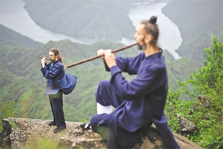 8月10日、十堰市の白馬山天馬峰の頂上で、中國の伝統(tǒng)楽器「洞簫」や「竹笛」の練習をするアイルランド人のエレンさん（寫真左）とポーランド人のダリウスさん（寫真右）。