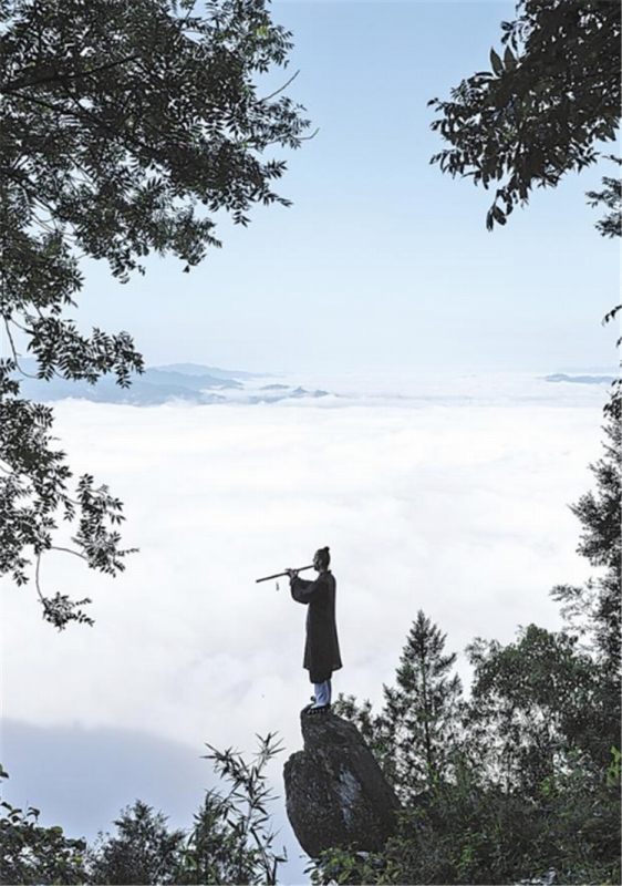 8月19日、白馬山天馬峰の頂上の石の上に立ち、眼前に雲海が広がる中、中國の伝統(tǒng)楽器「洞簫」の練習をするポーランド人のダリウスさん。