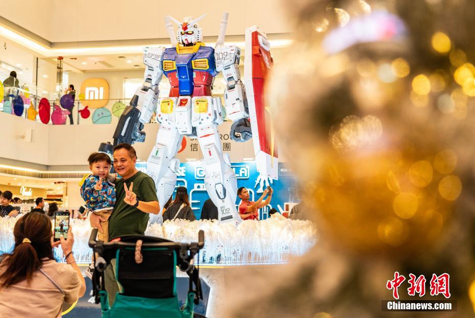 高さ3メートルの初代ガンダムRX-78-2の立像の前で記念撮影する市民や観光客（撮影?侯宇）。